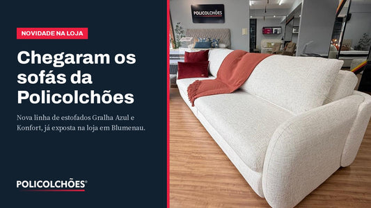 Sofá branco de tecido texturizado com manta terracota e poltrona orgânica expostos na loja Policolchões em Blumenau — nova linha de estofados