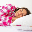 Mulher deitada na cama com o travesseiro IWS Magnum Pluma AirFiber
